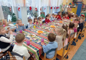 Dzieci siedzą przy stole - słodki poczęstunek.